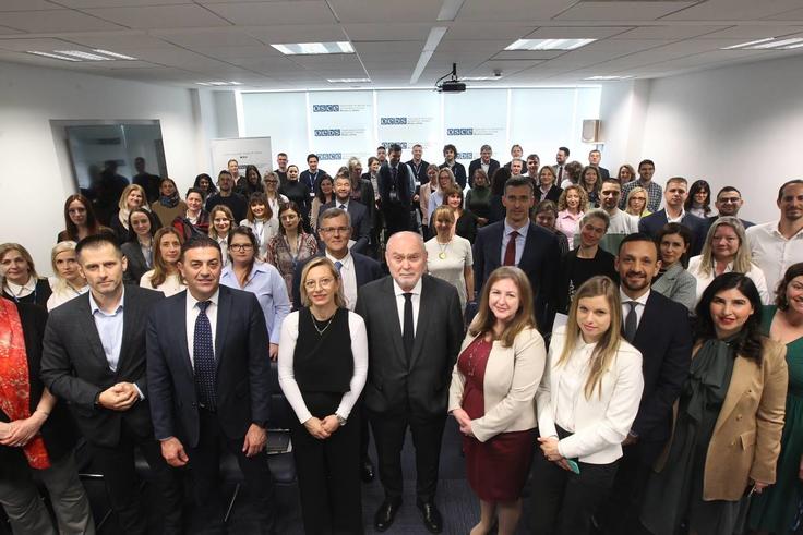 A large group of people in business attire gathered in a conference room.